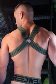 Person wearing a green harness with 'Breedwell' branding in a dark setting.